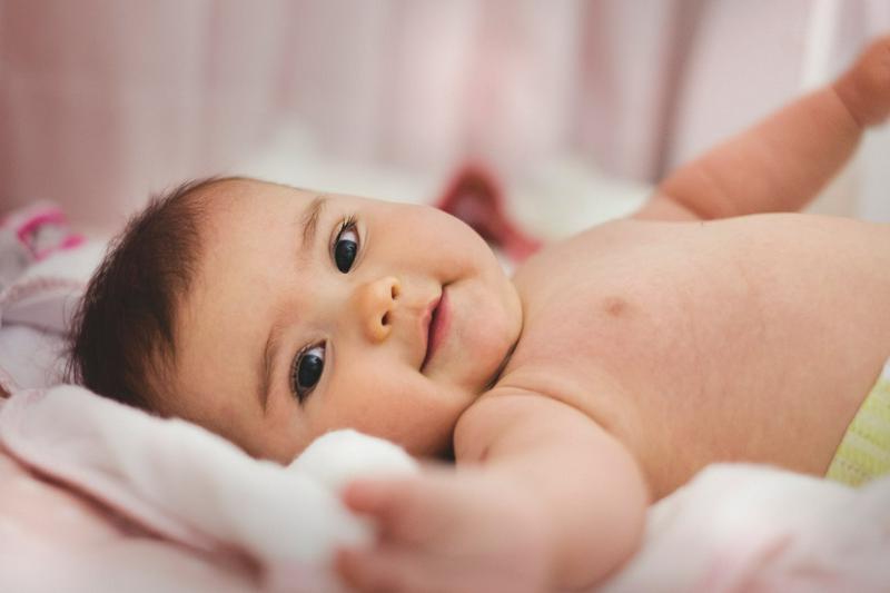 A baby lies on a bed.