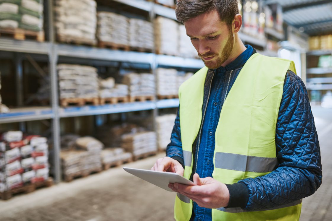 young man working in warehouse looking at inventory on a tablet