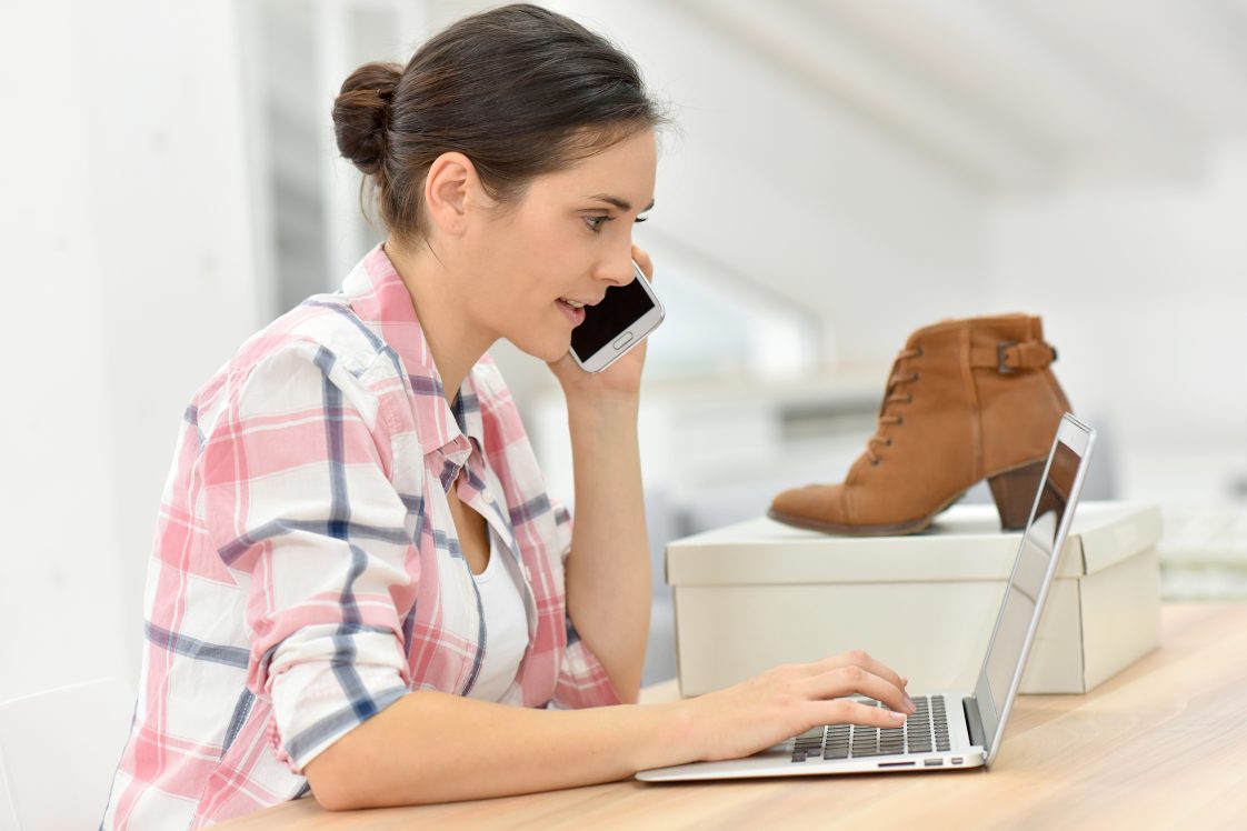 woman on phone after opening package with shoes she ordered