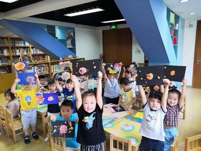 A group of children held up handmade paintings.